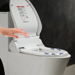 Person reaching for a disposable toilet seat liner dispenser mounted on the bathroom wall.