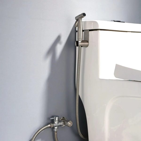 Photorealistic image of a hand holding a stainless steel bidet sprayer next to a toilet, showcasing its integration into a bathroom routine.